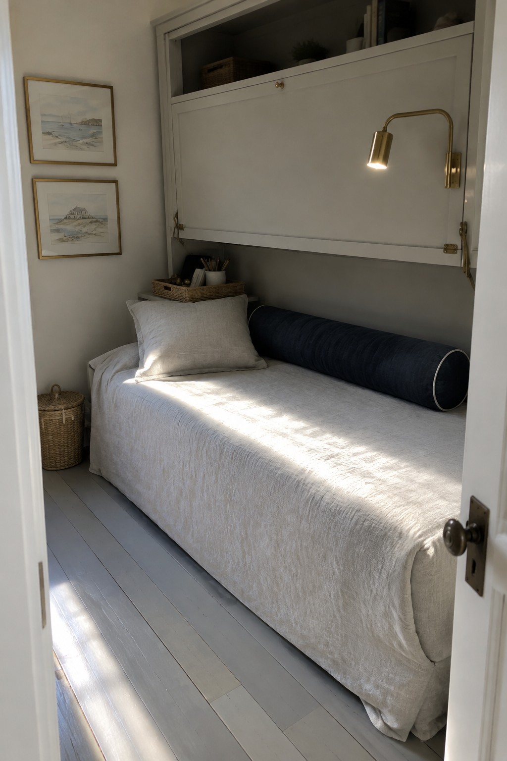 A white-covered daybed sits beneath a folded-down wall cabinet in a narrow room.