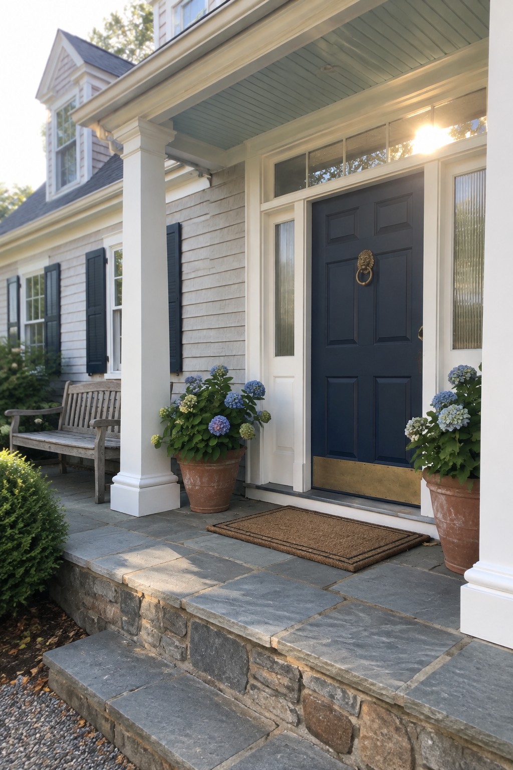 A dark blue front door with brass hardware sits in a white-trimmed entry beneath a covered porch.