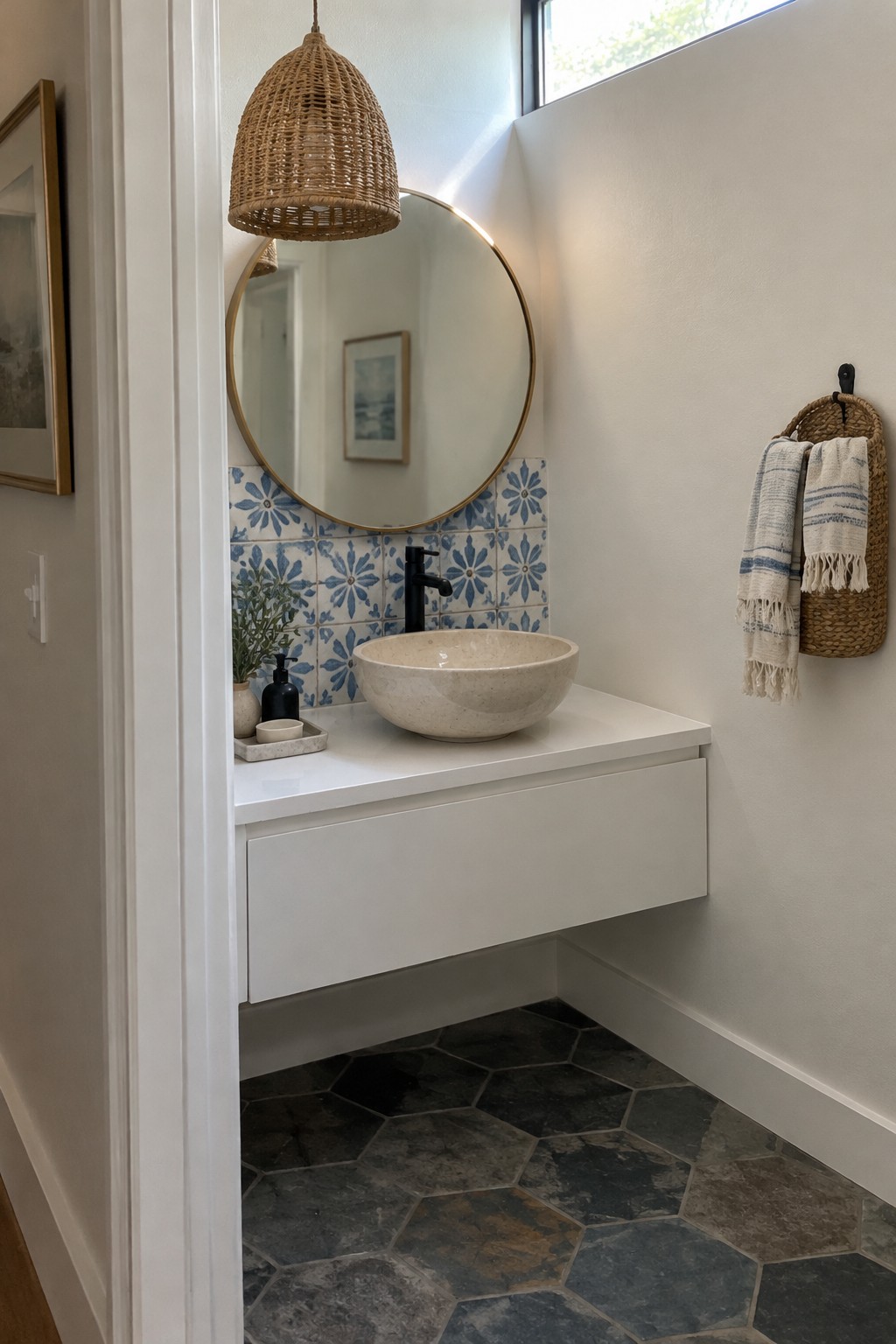 A bathroom vanity with a woven pendant, round mirror, blue patterned tile, and a bowl-shaped vessel sink.